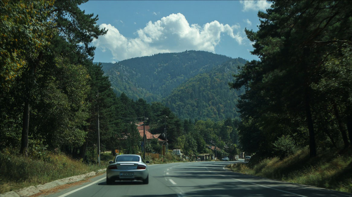Automobil na planinskom putu u Srbiji, okružen šumom i brdima